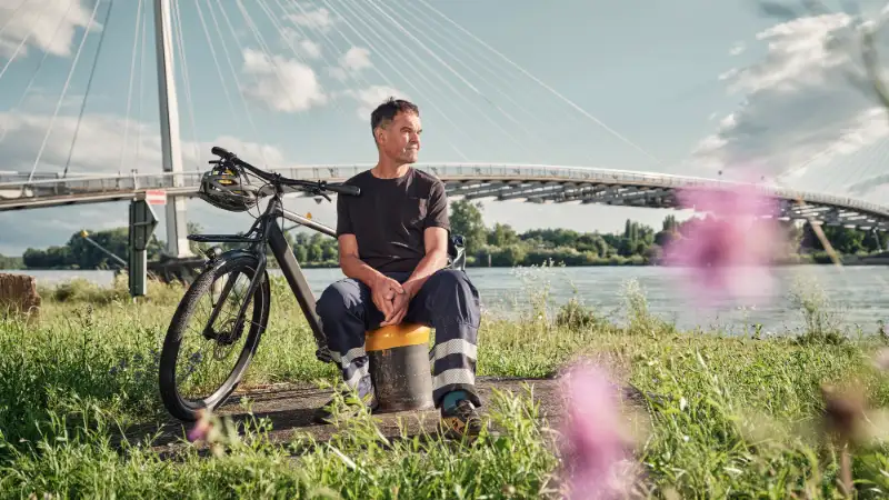 JobRadler Arbeitskleidung sitzt Wiese Brücke