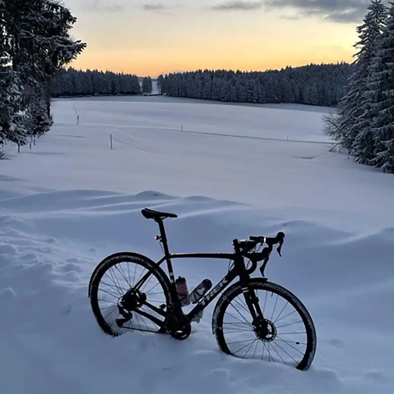 Ein Jobrad im Tiefschnee im Winterwald, es dämmert.