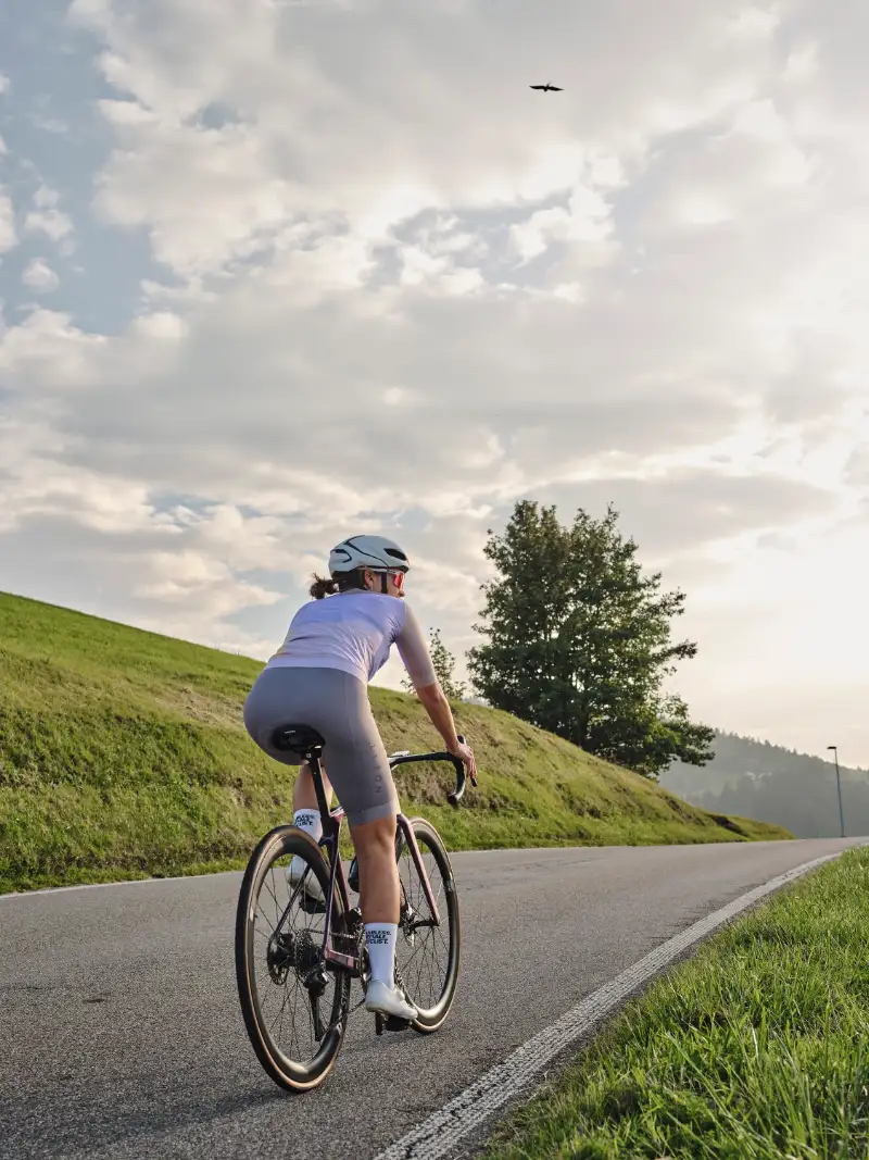 Rennradlerin fährt auf Straße Richtung Horizont