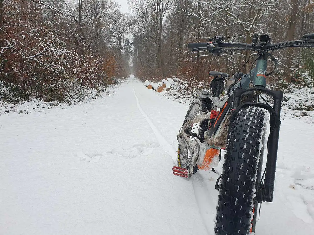 Ein Mountainbike auf Waldweg im Schnee, im Hintergrund Wald - JobRadmoment eines Jobradlers